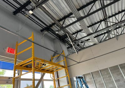 Inside the construction site, MD's skilled team from Nextt Commercial Builders navigates through scaffolding and exposed ceiling beams under the glow of an EXIT sign.