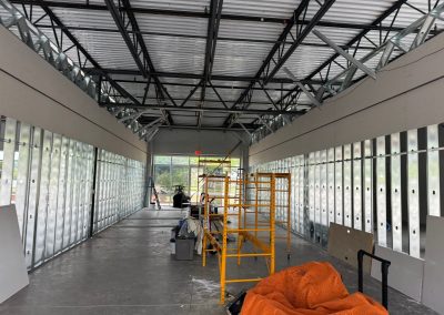 The interior reveals an unfinished commercial construction site in Rockville, with metal studs and scaffolding towering over scattered materials on the floor, a testament to the expertise of skilled commercial builders.