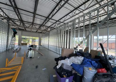 The interior of a building in Rockville is under construction, with metal frames and scattered materials on the floor. Nextt Commercial Builders is at the helm, ensuring every detail aligns with the highest standards for future occupants.