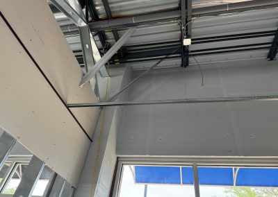 The interior construction site in Rockville showcases exposed metal beams, wiring, and partially installed drywall near a large window. MD Commercial Builders are meticulously crafting this space to ensure quality and precision in every detail.
