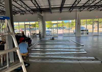 In a sunlit room in Rockville, an MD commercial builder skillfully assembles metal beams on a concrete floor, surrounded by large windows.