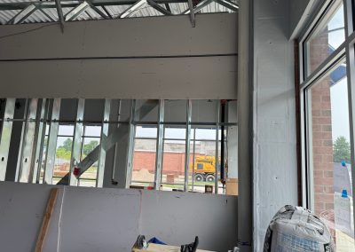 Interior construction site in Rockville with unfinished walls, metal studs, and a window showcasing commercial construction equipment outside.